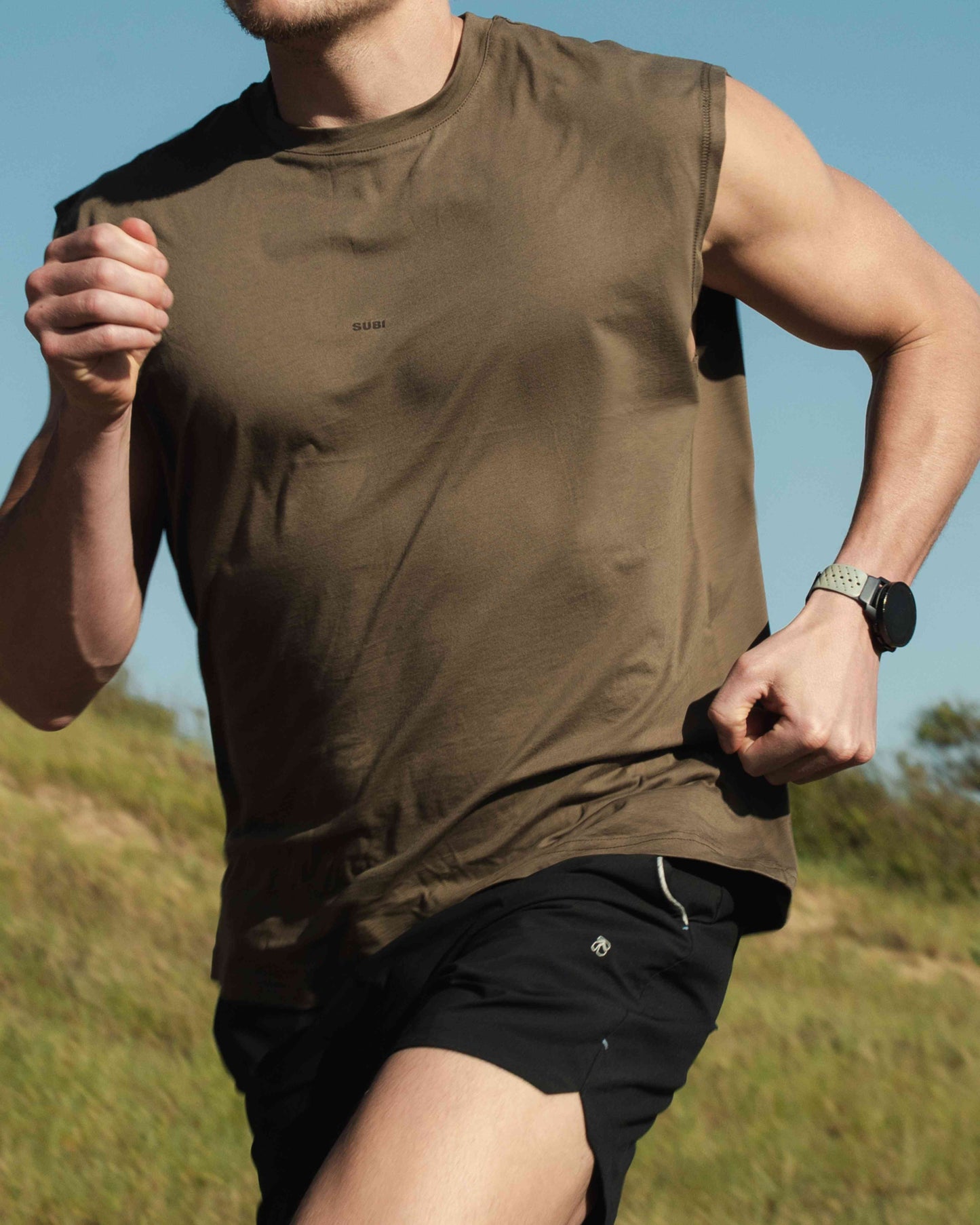 Model in training tank top, Dune colour, front view, relaxed fit, wide arm openings
