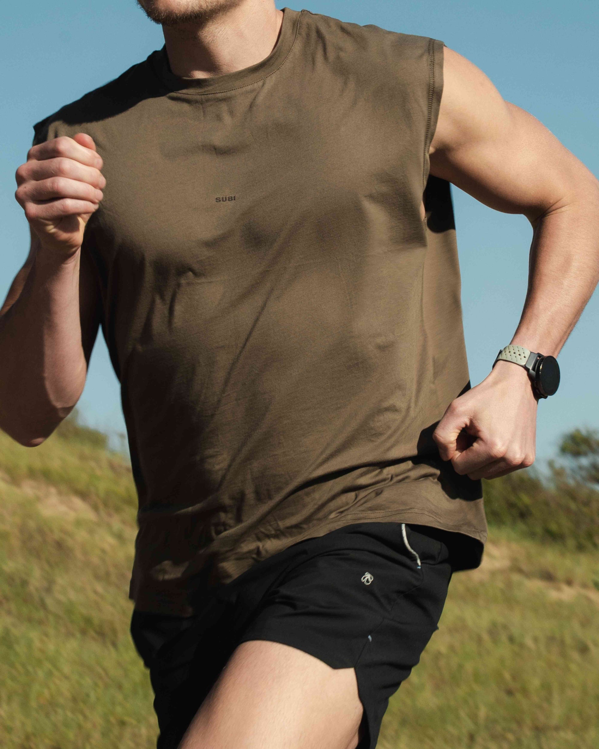 Model in training tank top, Dune colour, front view, relaxed fit, wide arm openings
