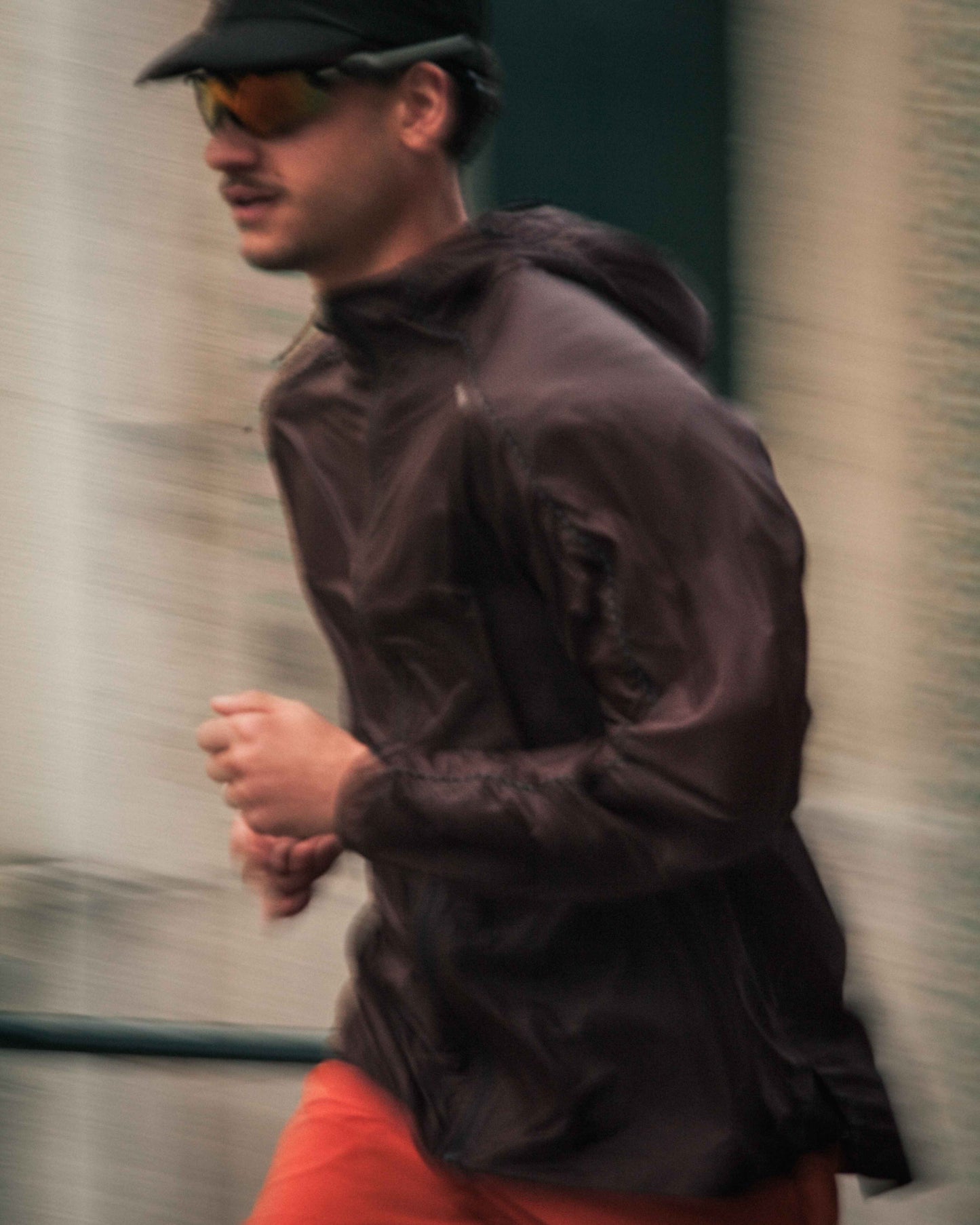 Model running in lightweight jacket, Brown colour, functional fit, zips.
