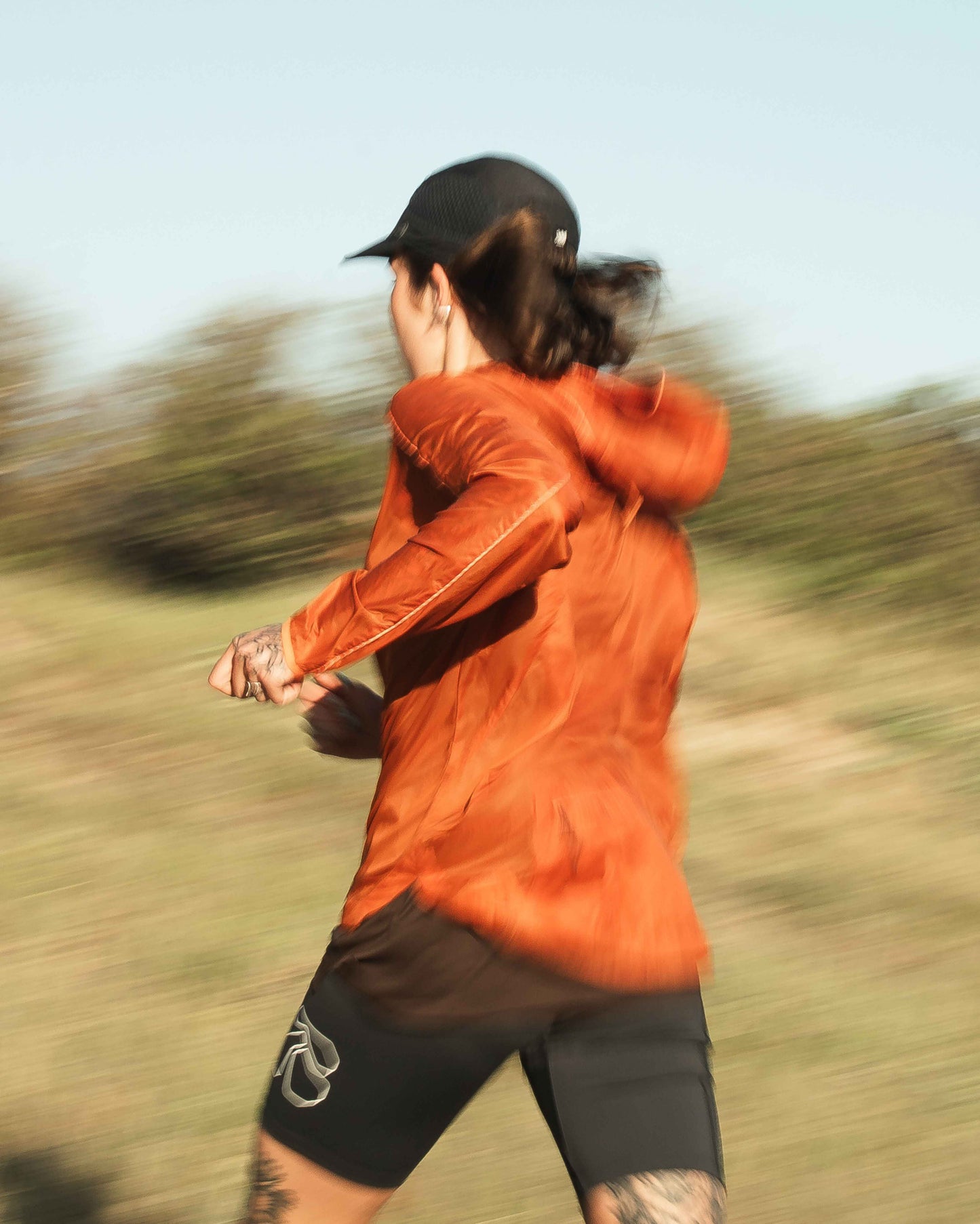 Model running in lightweight jacket, Rust colour, functional fit, back zips.

